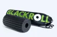 Sort foam roller med skrå savtakkede riller på overfladen, liggende foran en sort Blackroll-gymnastikpose
